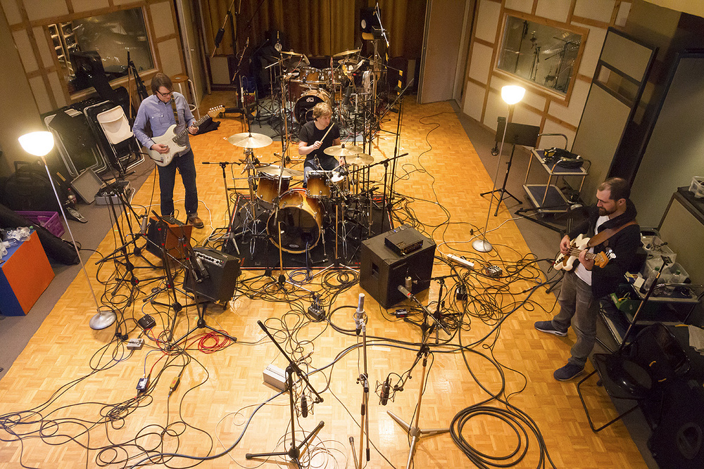 Image représentant une vu de haut d'une session d'enregistrement d'un groupe de musique dans un studio vintage.
